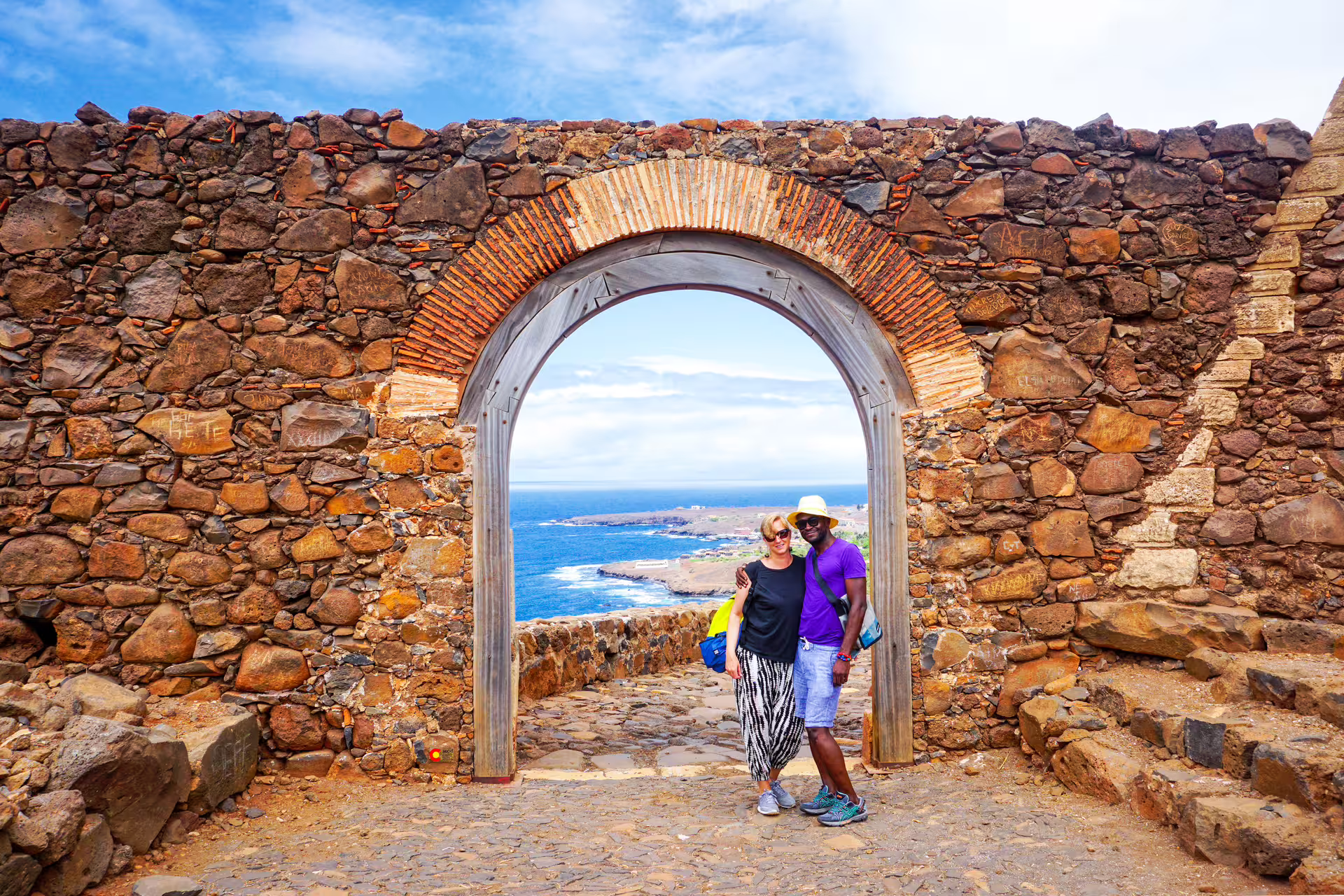 Couple under stone arch at Fortaleza Real de São Filipe, Cidade Velha UNESCO tour with Atlantic coast views