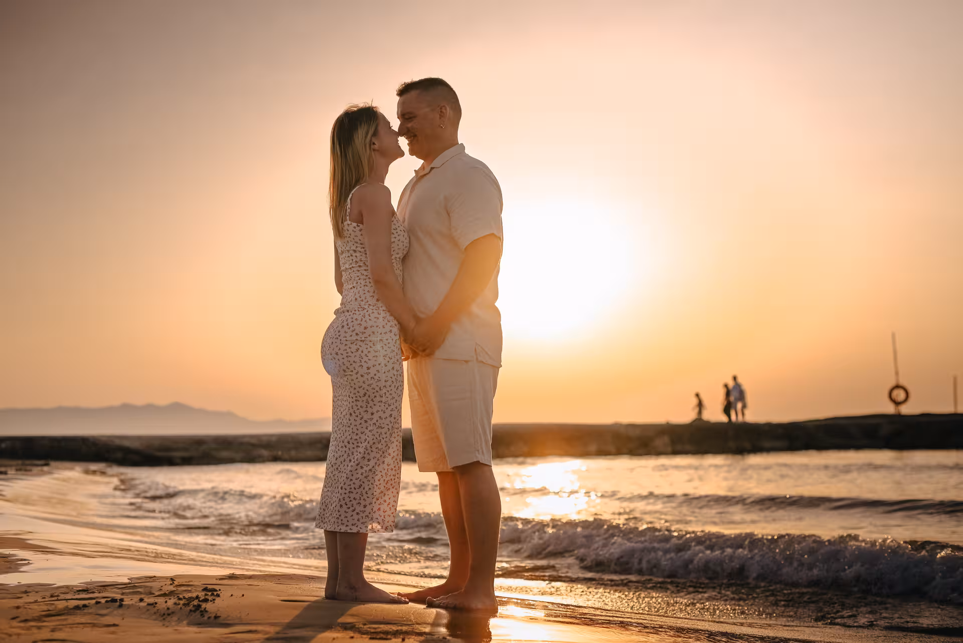 Happy couple standing close on Analipsi beach at sunset, ideal for capturing intimate moments in a photoshoot.