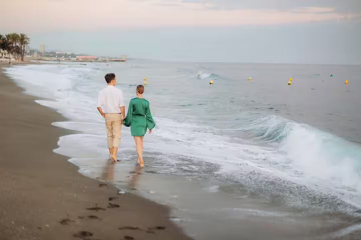 Couple walking along the serene Marbella shoreline at sunset, enjoying a private beach photoshoot experience.