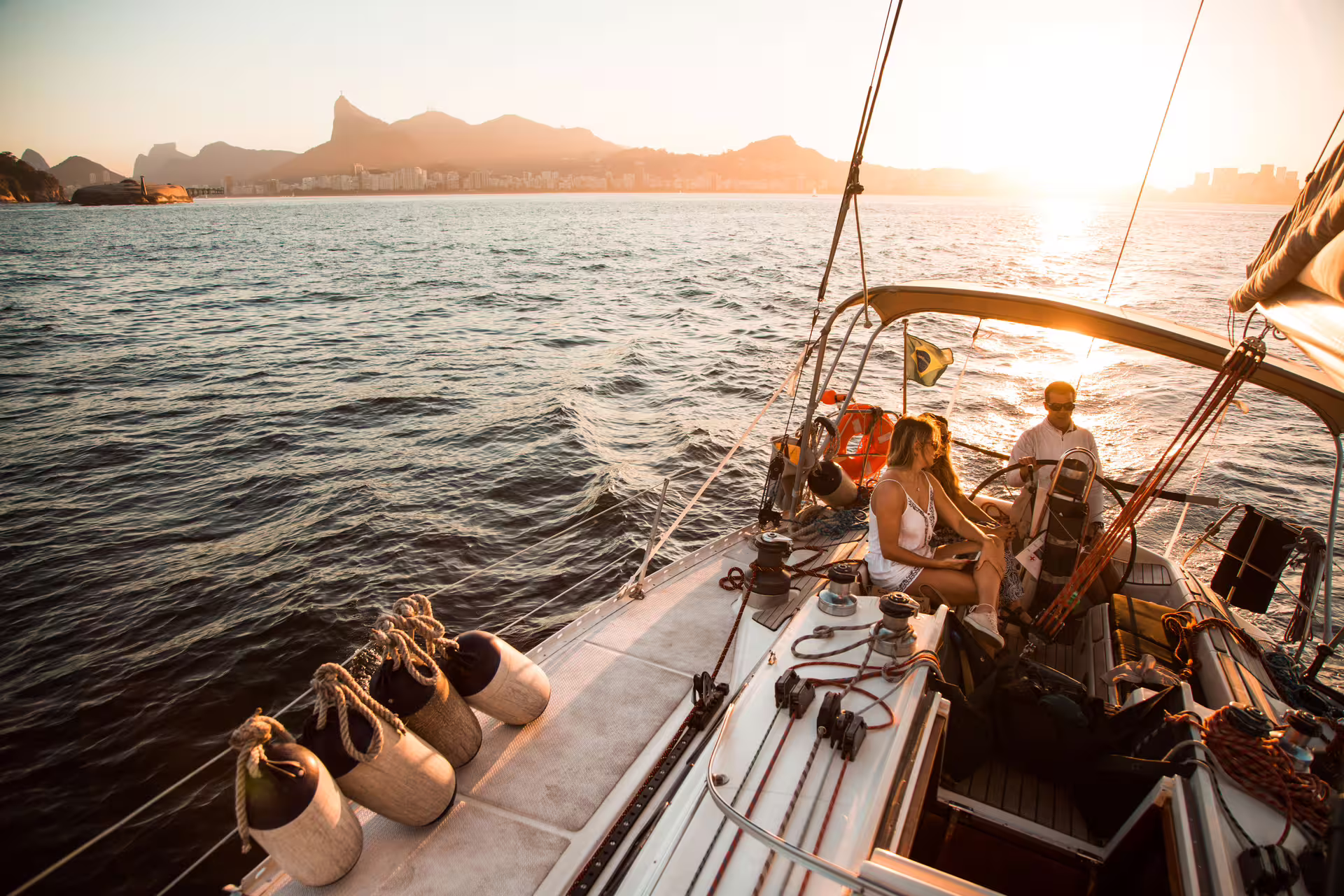 Couple enjoying a sunset sail in Rio de Janeiro, with stunning views of the coastline and mountains.