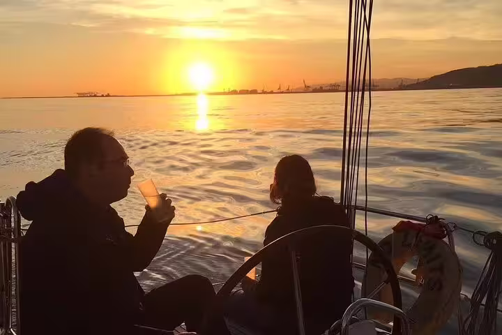Couple enjoys a 2-hour sunset sailing experience with open bar and tapas, watching the sun set over calm ocean waters.