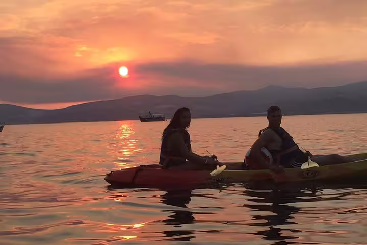 Couple kayaking at sunset near Split on the Adriatic Sea, joining a guided sea kayaking tour with wine