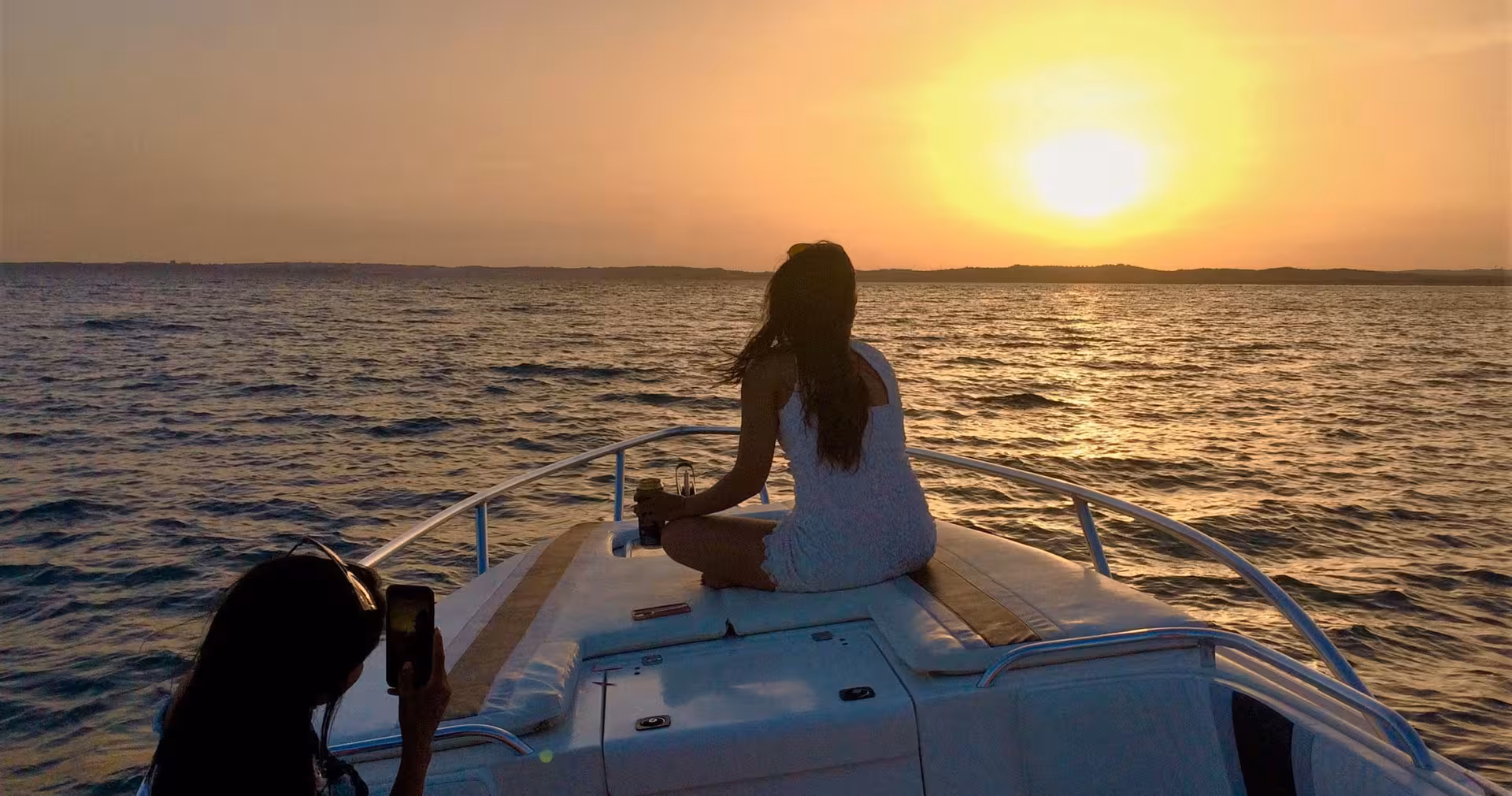 Couple relaxing on a yacht at golden hour, capturing a romantic ocean sunset on a private Algarve boat tour