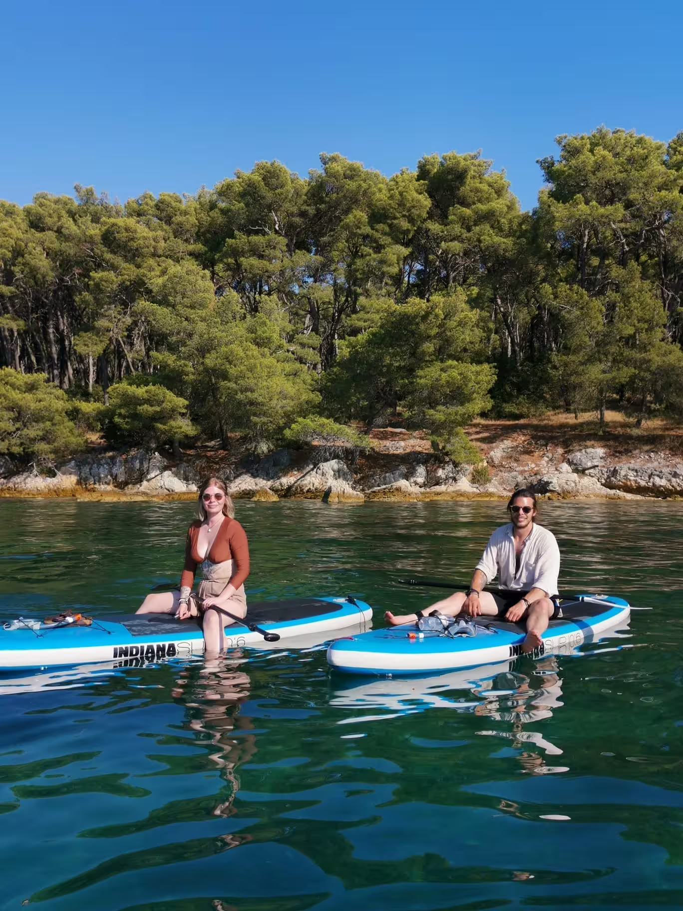 Couple relaxing on SUP boards in a sheltered bay on the Split morning stand up paddle tour along the Adriatic coast