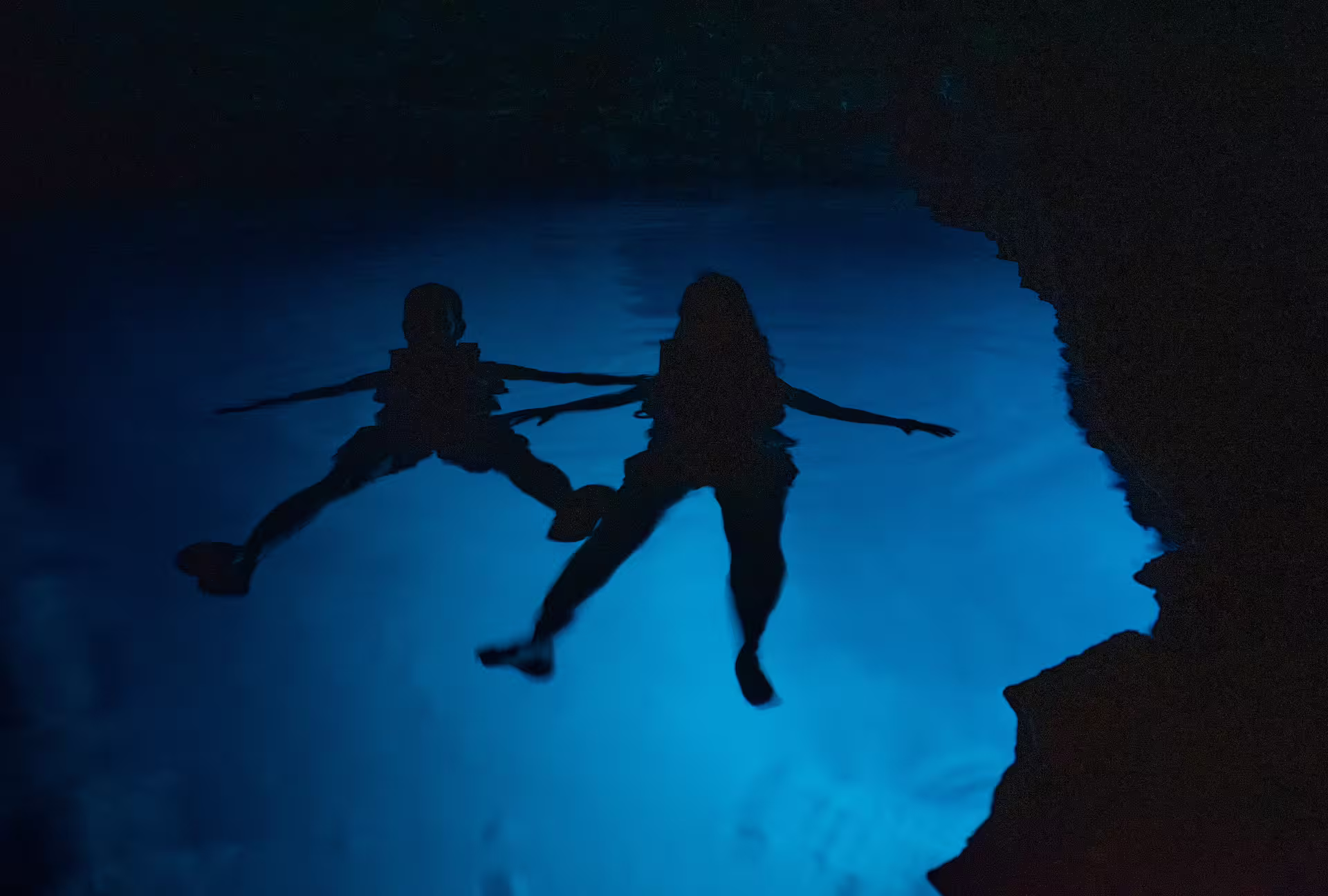 Couple floating in a sea cave’s blue water after SUP in Kardamyli, a coastal adventure in Mani, Greece