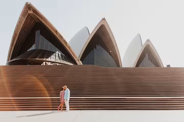 Couple posing at Sydney Opera House steps on a private tour with personal travel photographer in Sydney