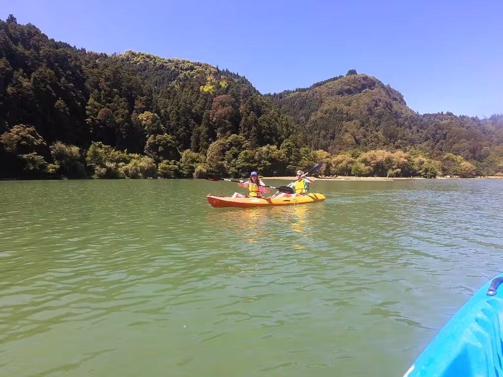 Couple paddling a tandem canoe on a green mountain lake, half-day guided tour with transportation included
