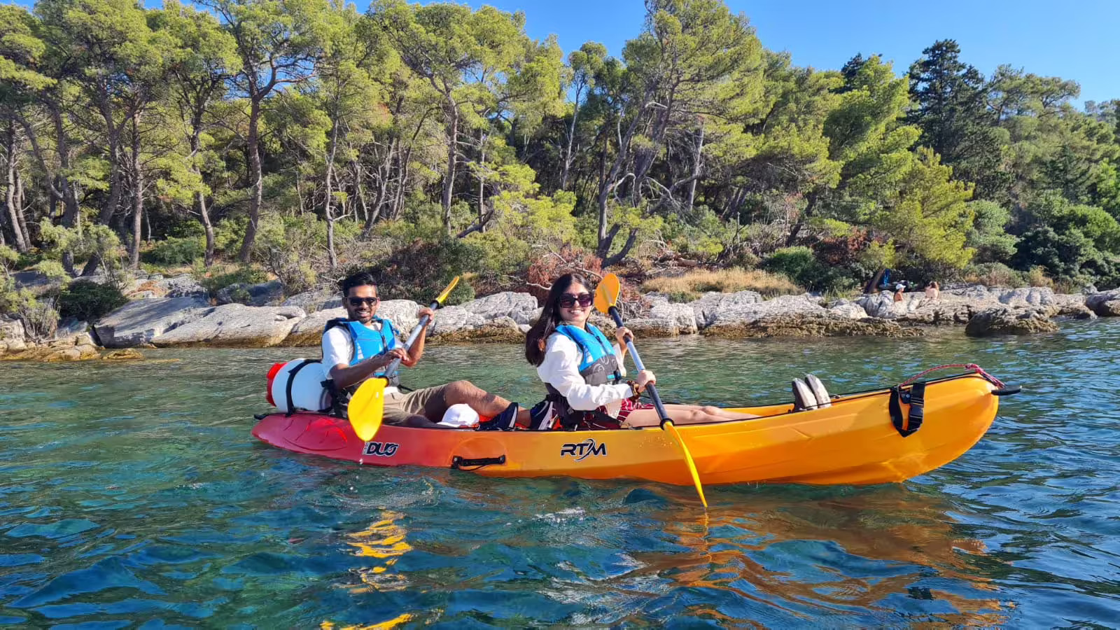 Couple paddling a tandem sea kayak in clear Adriatic water on a Split sea kayaking and snorkeling tour