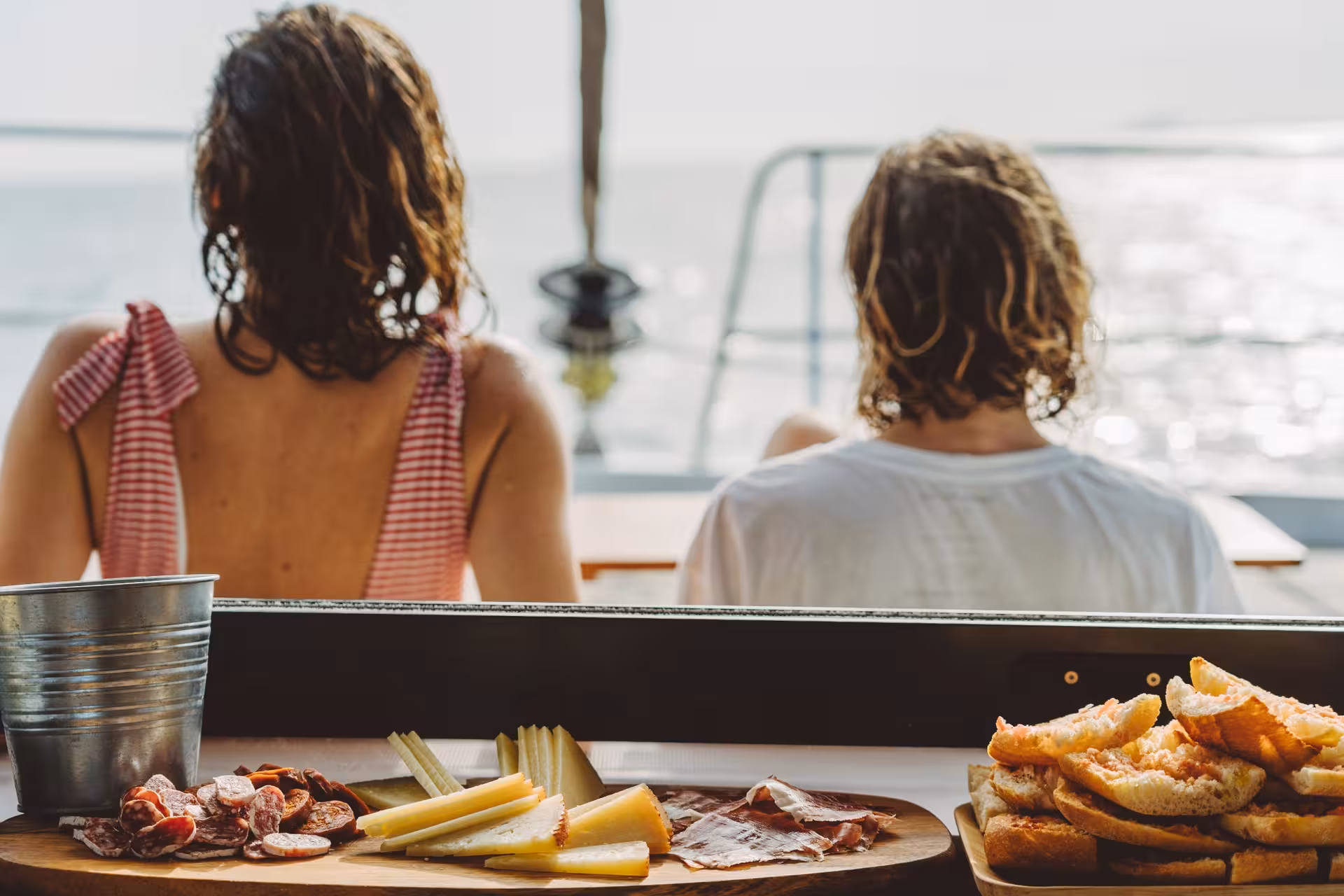 Couple enjoying onboard tapas on a private catamaran rental, relaxing at sea during a luxury cruise