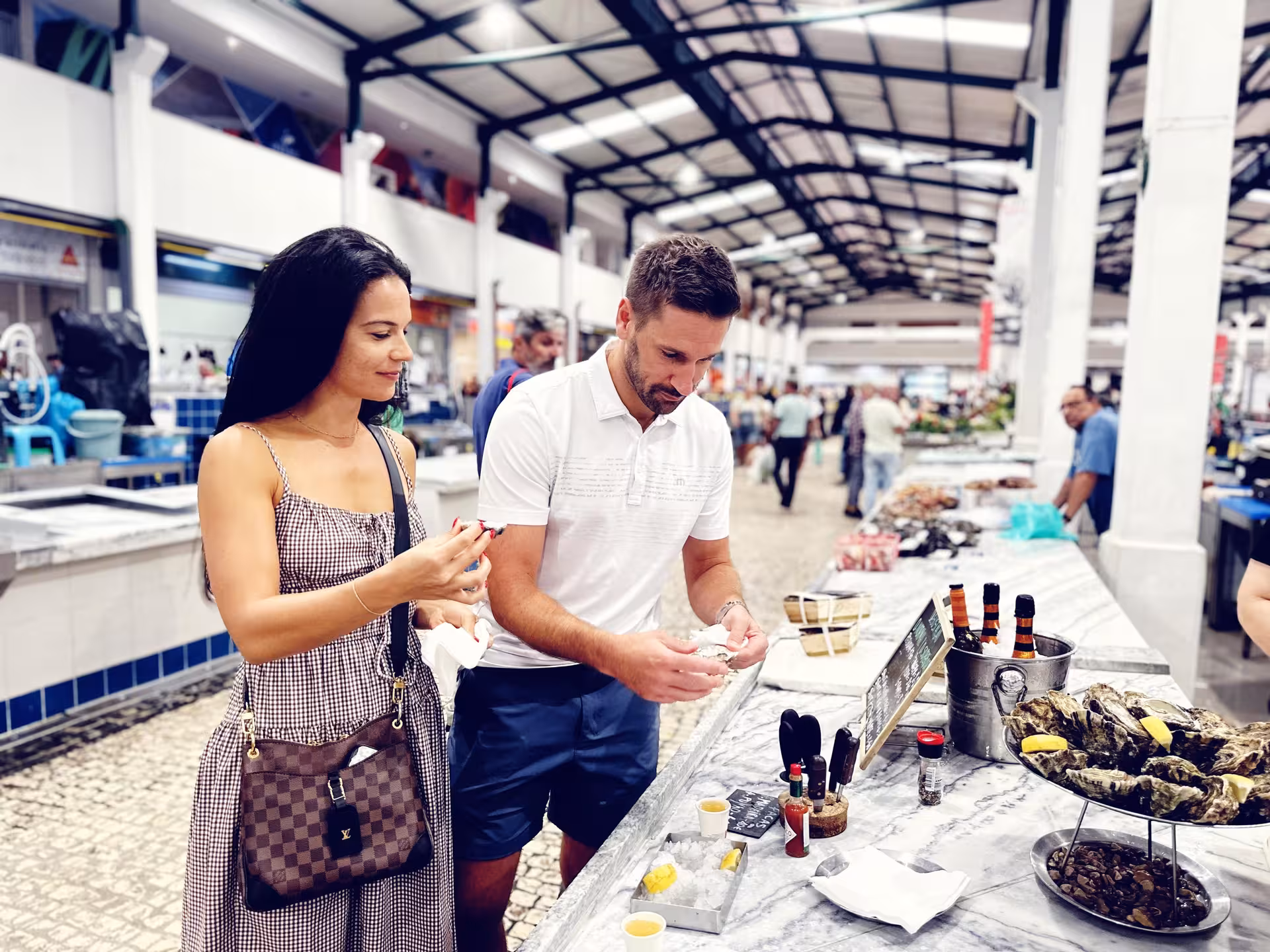 Couple tasting fresh oysters at Lisbon market, gourmet stop on private Arrábida wine tour and food tasting