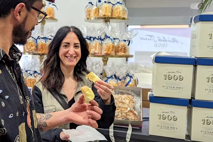 Couple tasting pandoro cake in a Verona bakery on a 1.5 hour food tour with tastings and sightseeing