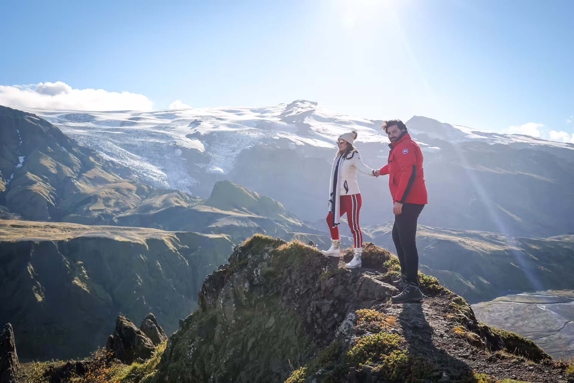 Couple holding hands on a rocky summit overlooking Thorsmork glacier valley on a full-day 4x4 tour from Reykjavik Iceland
