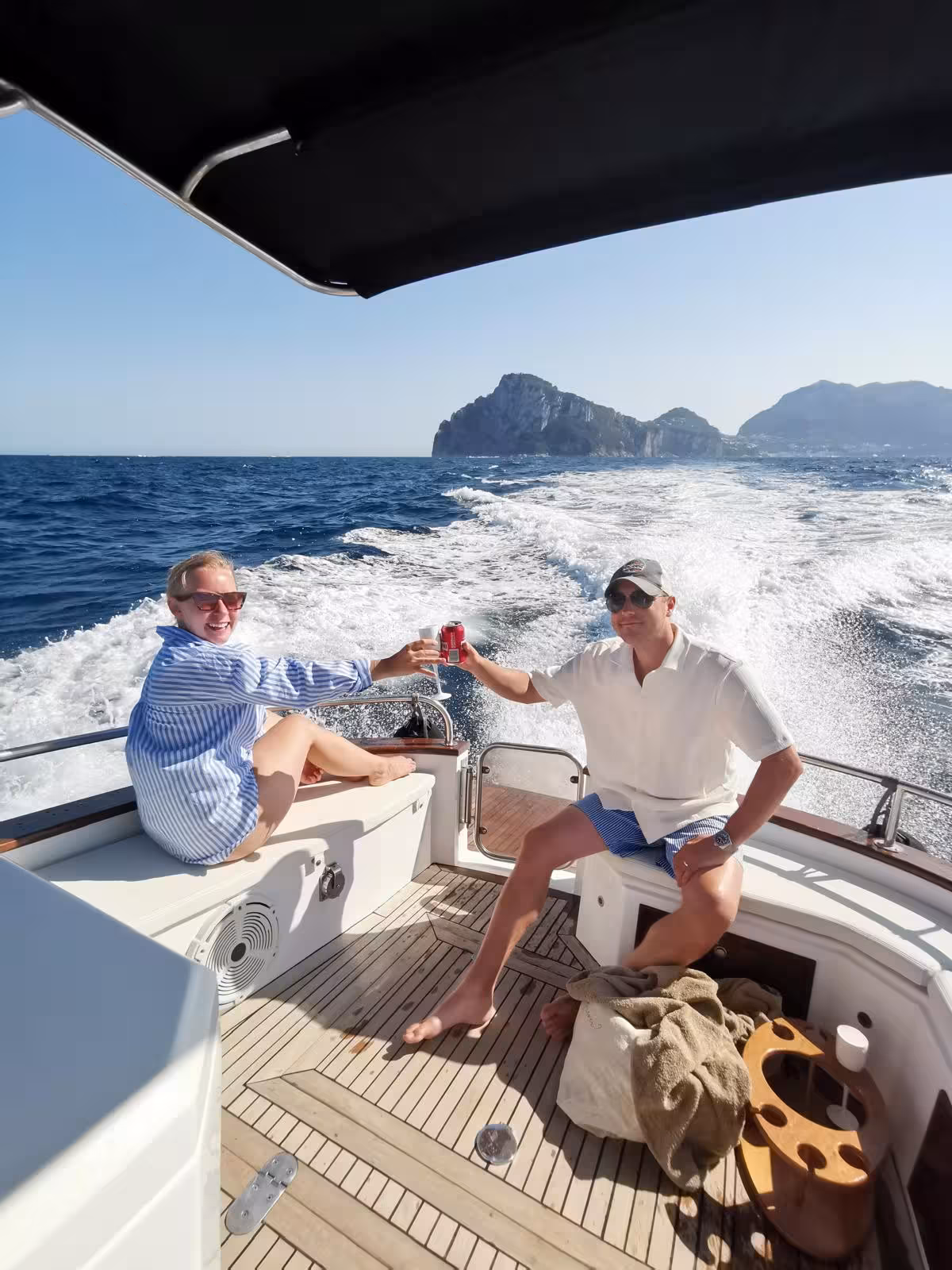Couple toasting drinks on a relaxing boat tour with stunning views of Capri's coastline.