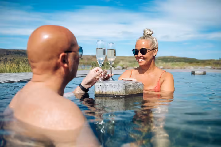 Couple toasting champagne glasses in Vok Baths geothermal pool in Iceland's Eastfjords