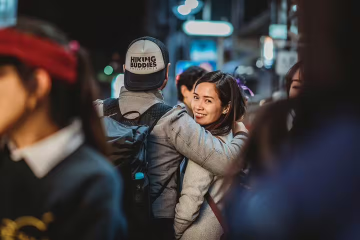 Couple hug in busy Tokyo nightlife street, shot on personal travel and vacation photographer tour with candid style