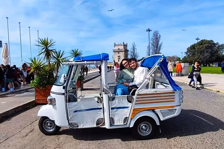 Couple riding a tuk tuk in Belém near Torre de Belém on a 2-hour private Lisbon tour with pastries