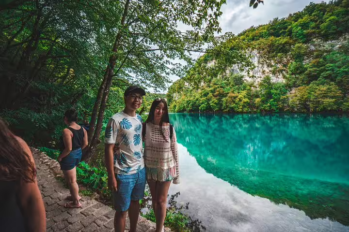 Couple posing by a turquoise lake at Plitvice Lakes National Park during a scheduled guided tour in Croatia