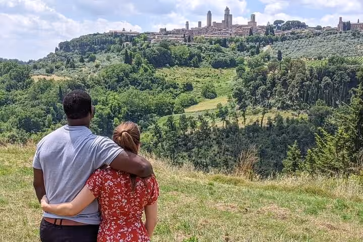 Couple enjoying a panoramic view of the Tuscan landscape with Siena's historic skyline in the distance on a day trip.
