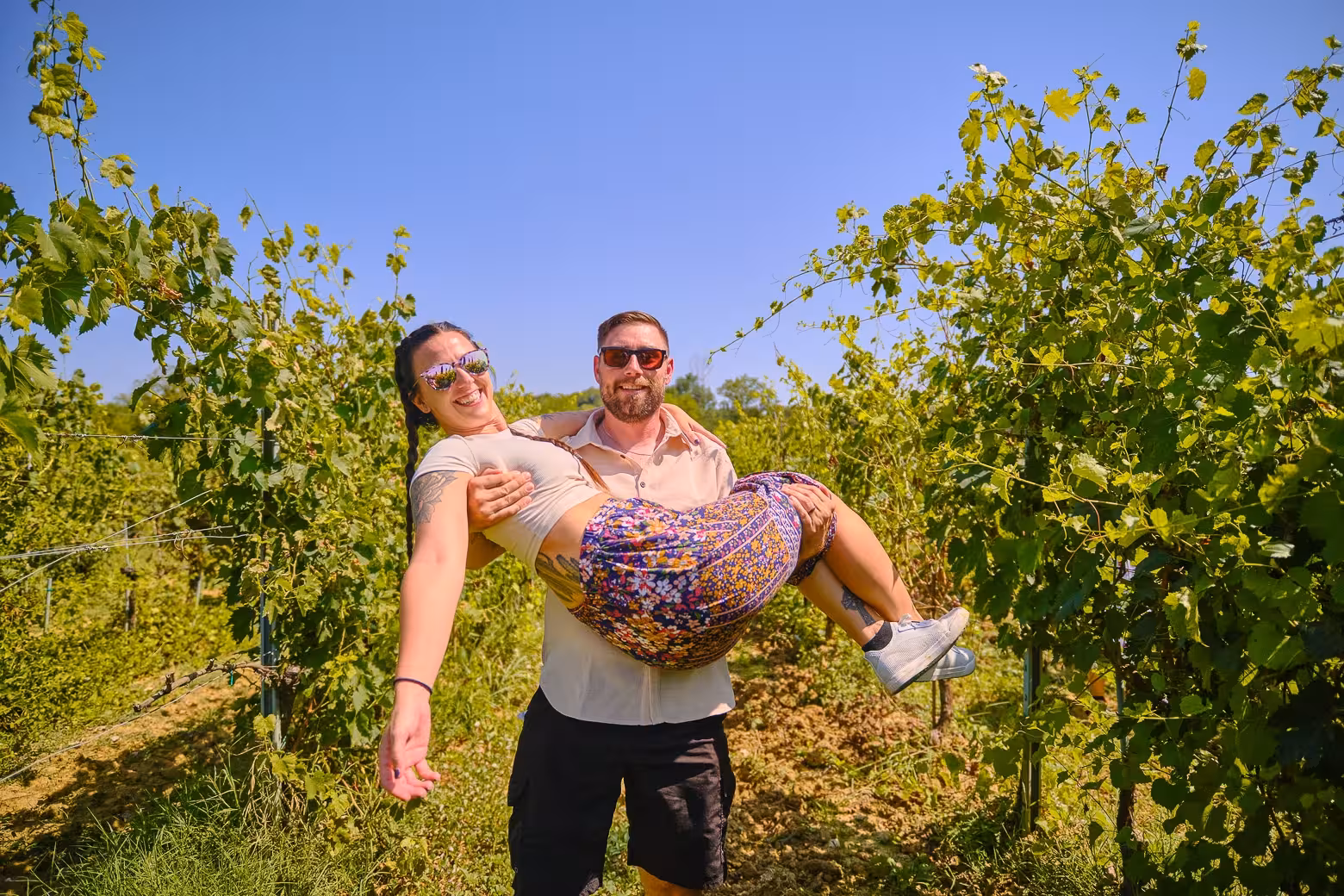 Couple enjoying a joyful moment in a lush Tuscan vineyard on a guided tour from Florence.