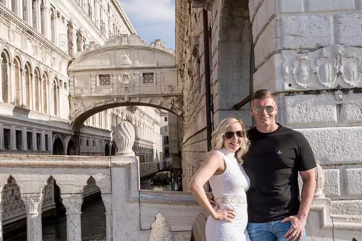 Couple posing happily near Venice's iconic Bridge of Sighs, capturing a memorable moment on a luxury photo tour.