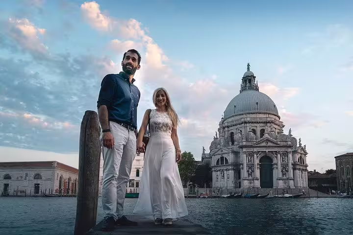 Couple standing by the Grand Canal with Santa Maria della Salute in the background during a Venice photo shoot.