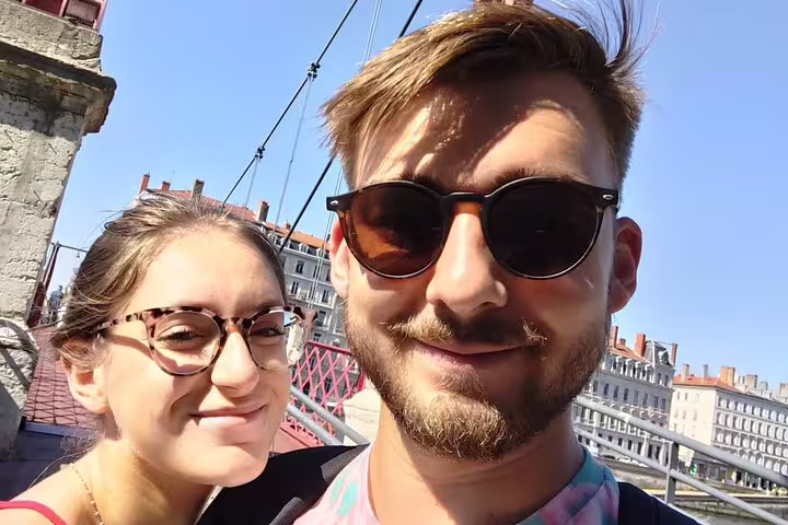 Couple smiling on a red pedestrian bridge during a walking tour in Lyon Old Town