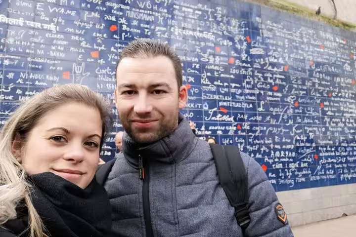 Couple smiling in front of the Wall of Love in Montmartre, Paris