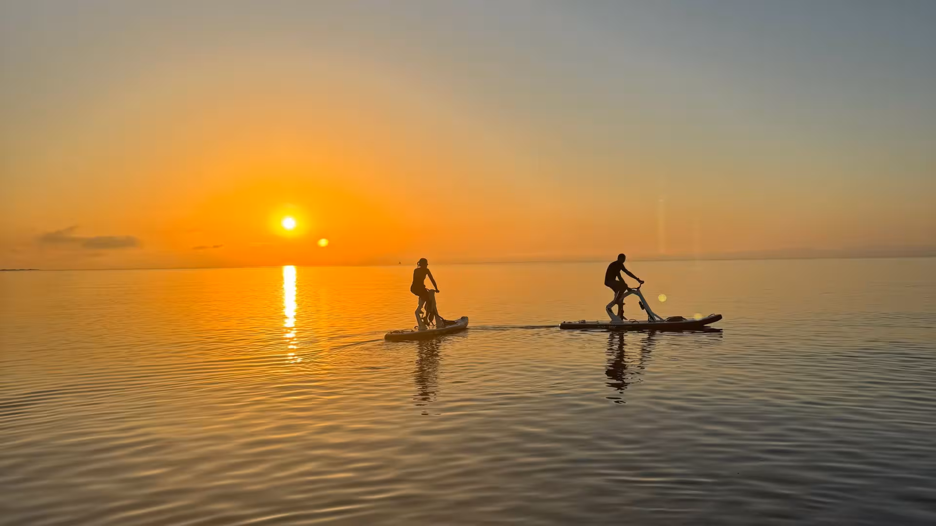 A couple rides water bikes on serene Porto Torres waters during a stunning sunrise, perfect for an adventure tour.