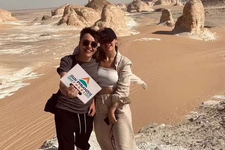 Couple at White Desert dunes with chalk rock formations on a private 2-day Jeep safari to Bahariya Oasis, Egypt