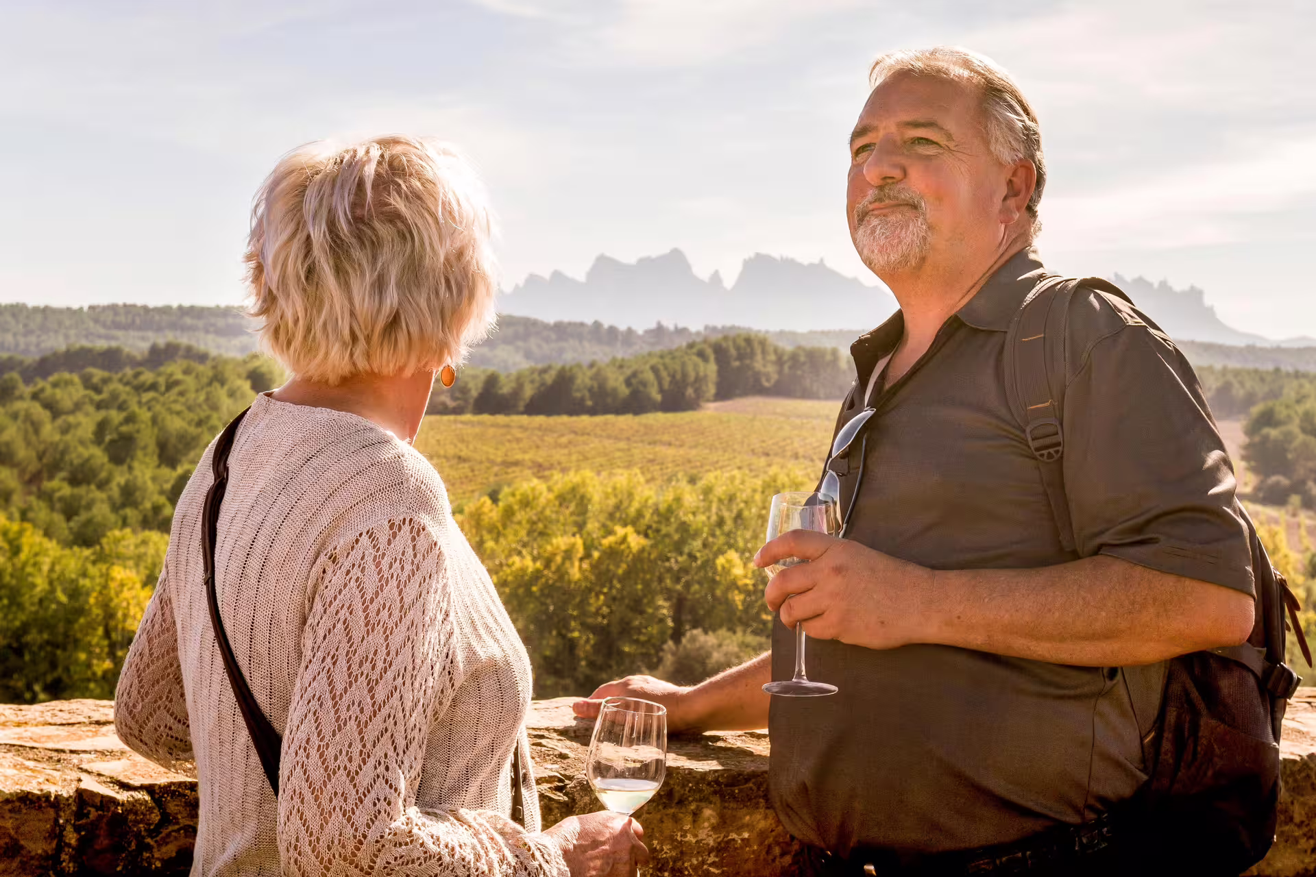 Couple enjoying wine with a scenic view of Montserrat mountains on a sunny vineyard tour.