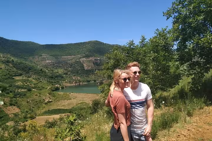 Couple posing with a scenic view of Berat's lush vineyards and rolling hills during the Wine Tasting & Food tour.