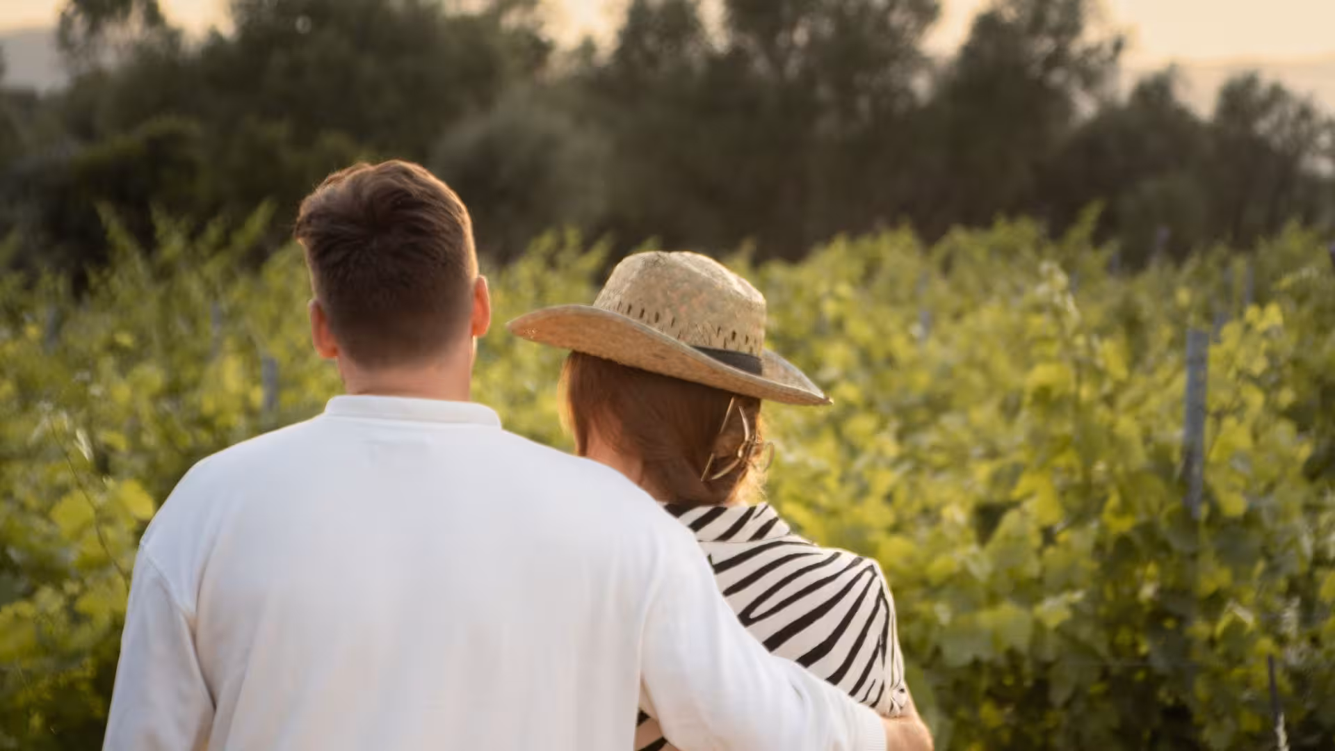 Couple embracing while exploring a vineyard during a wine tour in Gallura, Palau at sunset.