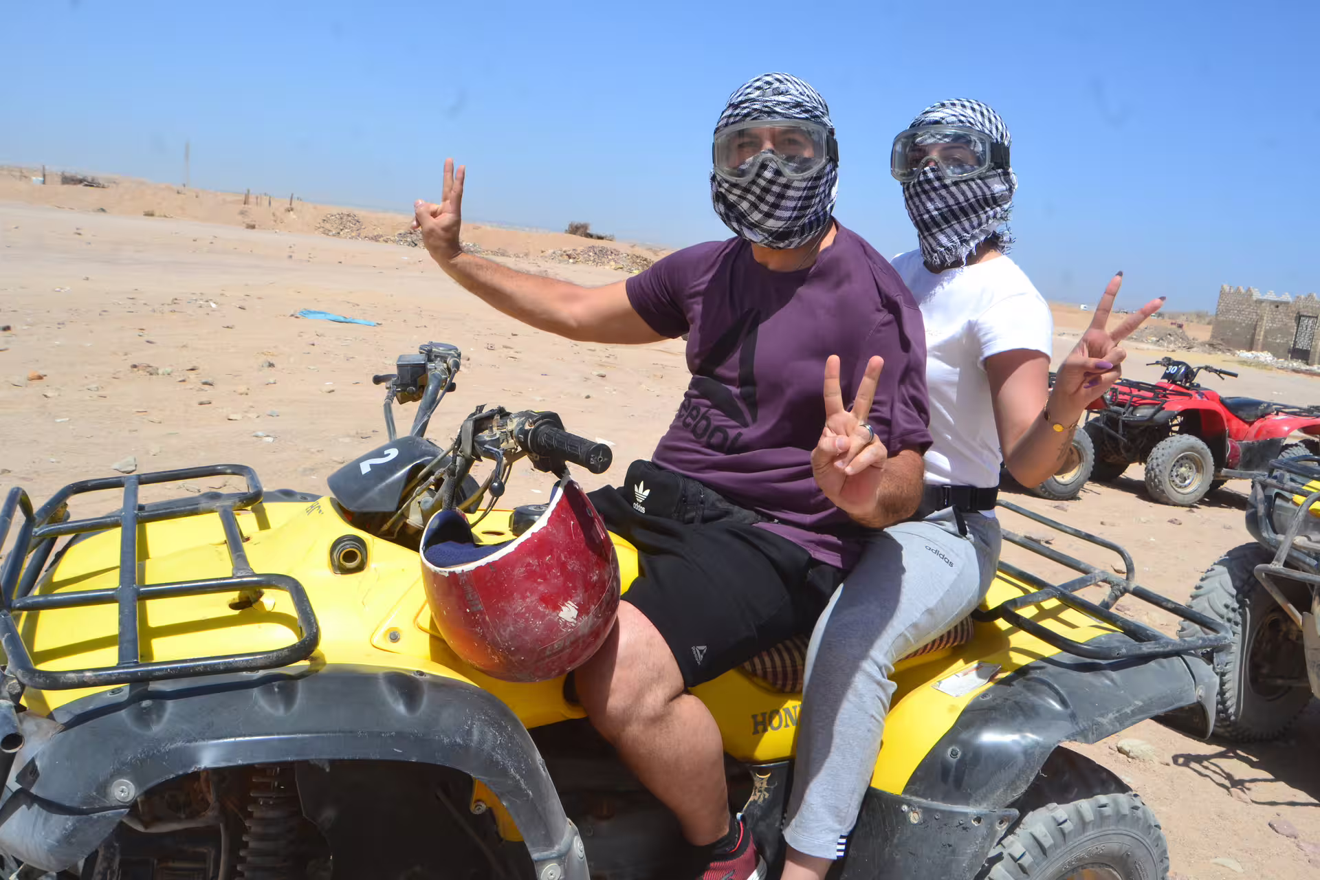 Couple wearing goggles on yellow quad bike in Hurghada desert, Egypt, during guided ATV safari tour