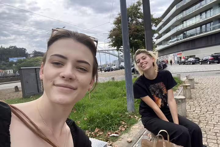 Two smiling women enjoying a self-guided walking tour along the waterfront in Porto, Portugal