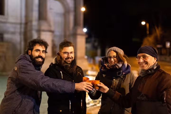 Group of friends toasting with drinks at a historic site in Rome on a craft beer walking tour.