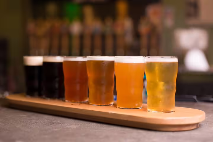 A selection of craft beers on a wooden tray, featured in the London Food & Drinks Private Tour of British taverns and pubs.