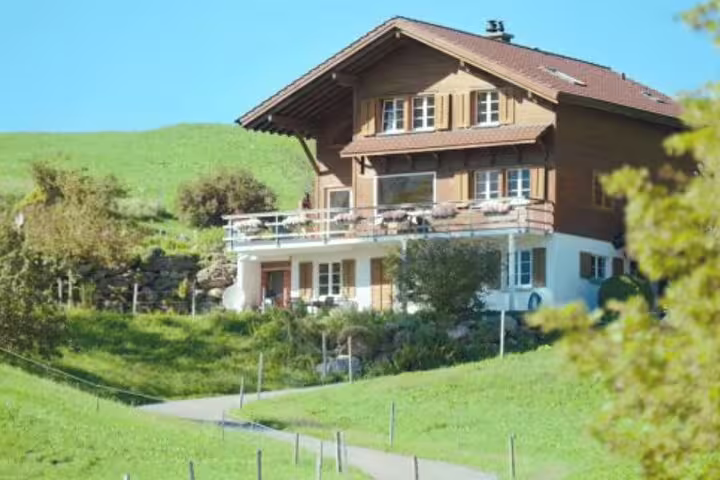 Traditional Swiss chalet surrounded by lush green hills, a highlight of the Crash Landing on You Private Tour in Switzerland.