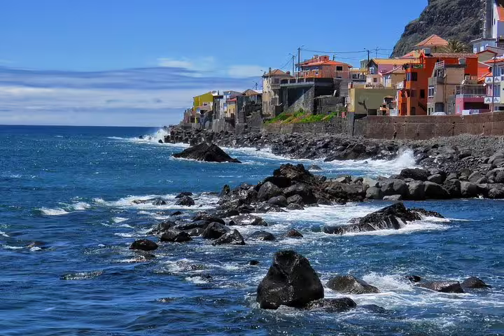 Vibrant coastal village with colorful houses along rugged cliffs by the ocean, ideal for adventurous 4X4 Craters of Fire tour.