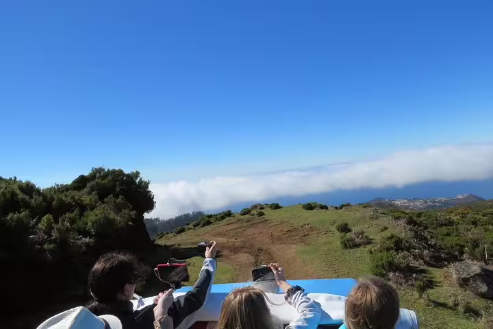 Tourists on a 4X4 adventure enjoy breathtaking views of rugged landscapes and distant blue horizon on the Craters of Fire tour.