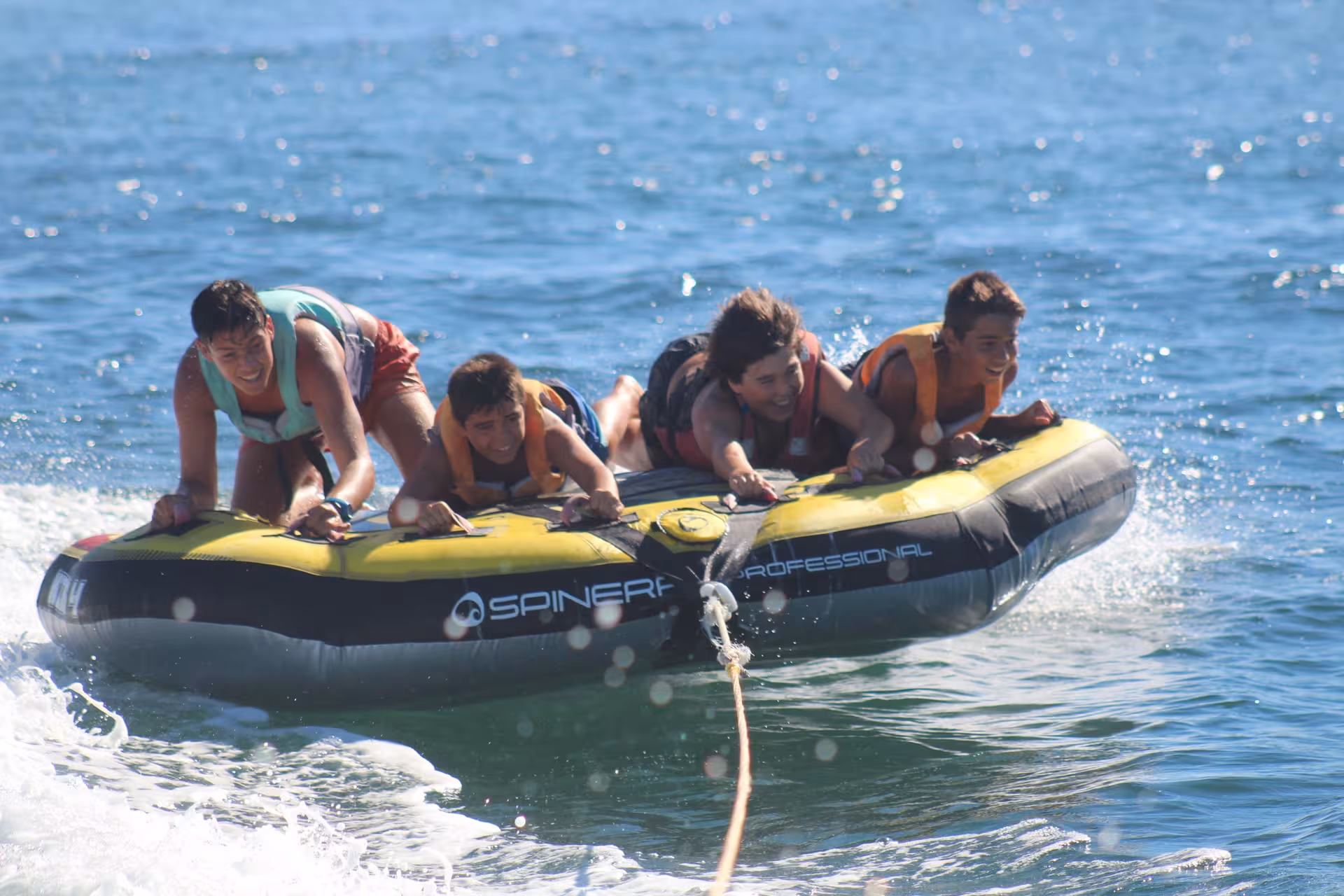 Group of young men laughing and holding on to a Spinera professional inflatable tube during an exciting Crazy Cookie water tubing adventure