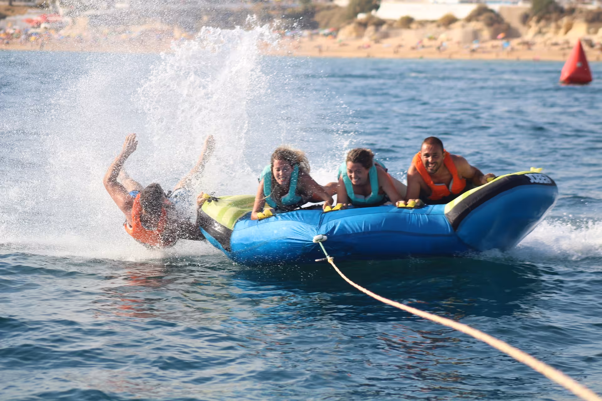 Thrilling Crazy Cookie tube ride with excited riders splashing into the ocean on a fun water sports adventure