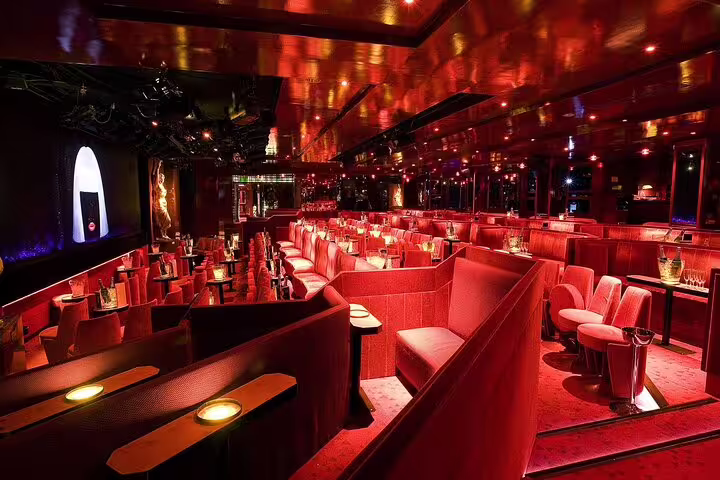 Red-lit interior of Crazy Horse Paris cabaret with plush booths and stage