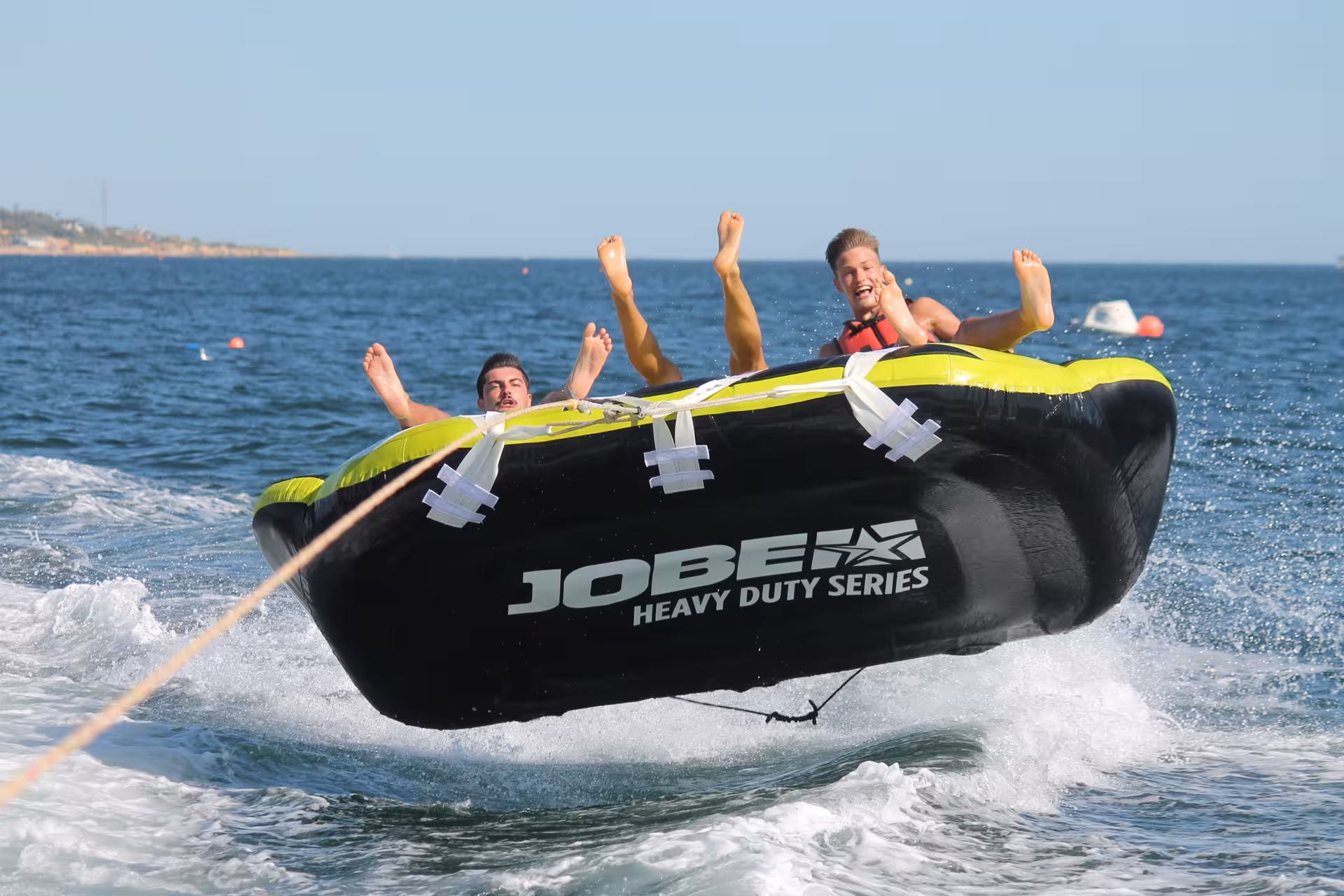 Thrilling Crazy Sofa ride with riders airborne on a Jobe Heavy Duty inflatable tube over ocean waves