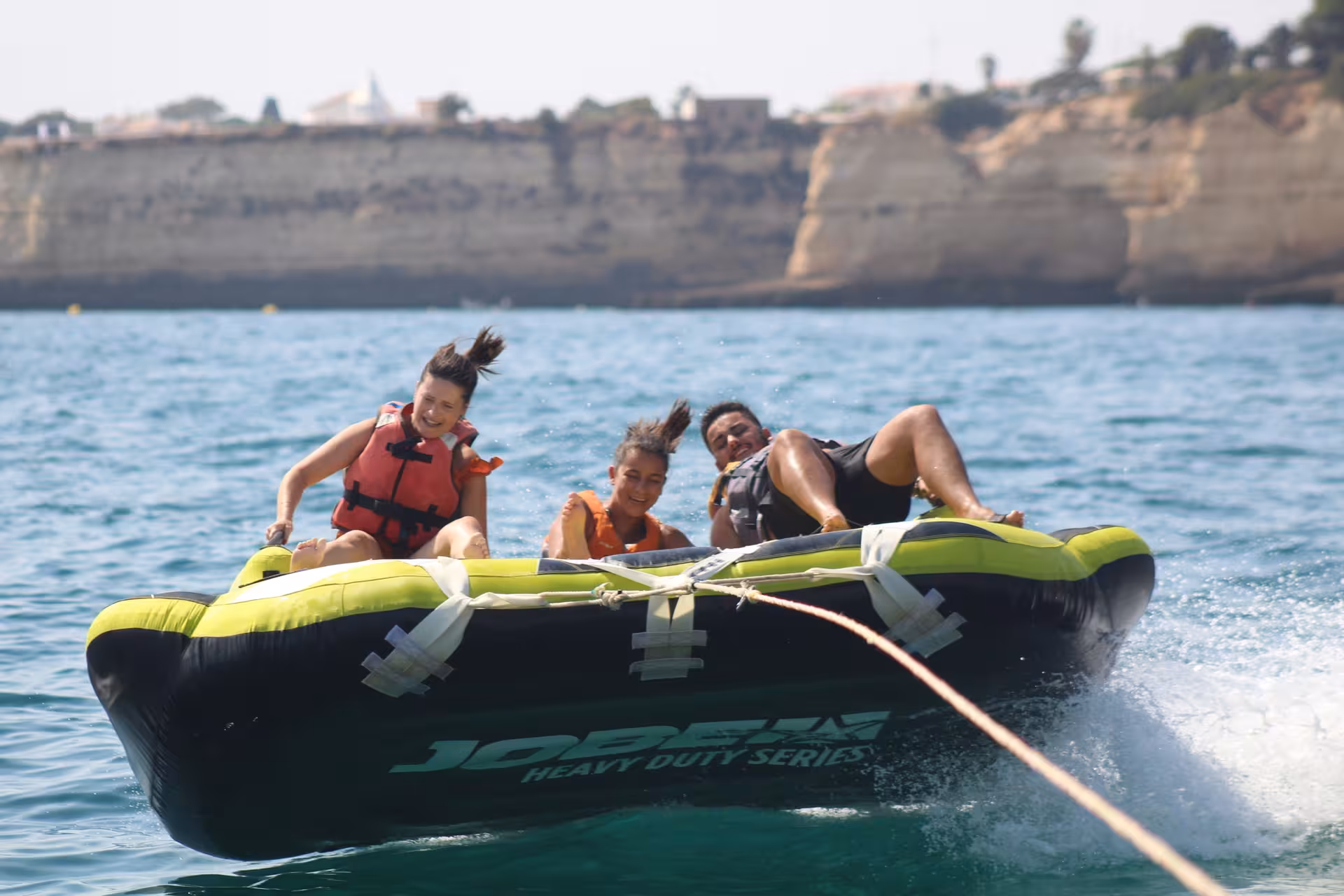 Group of three enjoying a wild Crazy Sofa Jobe heavy duty inflatable tube ride on the Algarve ocean