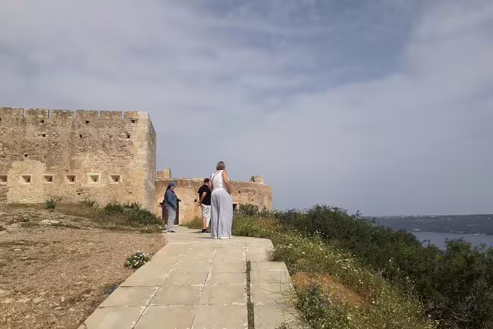 Tourists explore a historic fortress overlooking the sea on the Paths of Old Cretan Life tour near Chania.