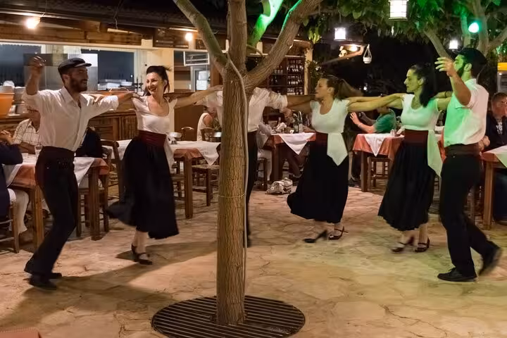 Traditional Cretan dancers perform in a taverna courtyard during Cretan Night with live music, food and dancing