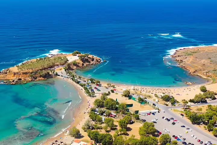 Aerial view of a picturesque Crete beach with azure waters, sandy shores, and lush greenery, perfect for a beach day in Chania.