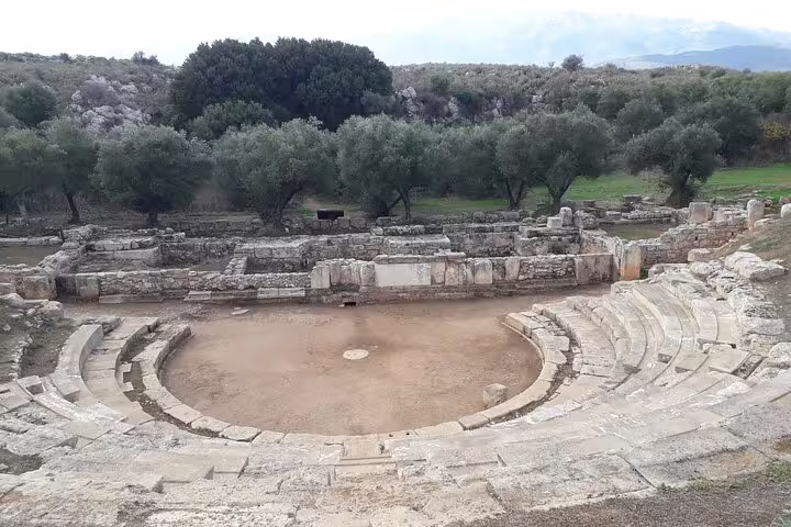 Ancient amphitheater ruins nestled among olive trees in the serene Crete countryside.
