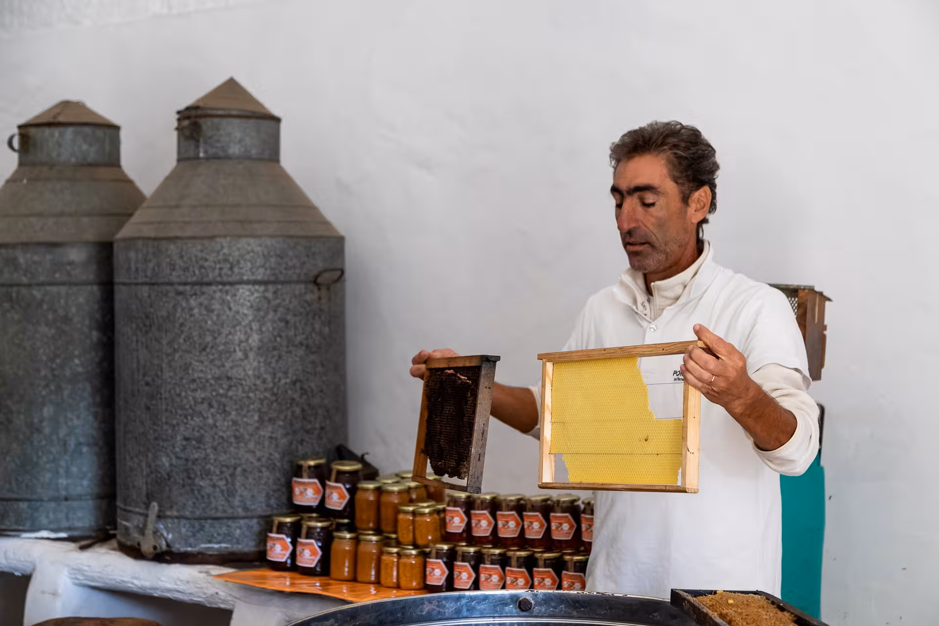 Local beekeeper demonstrating honeycomb frames and fresh honey jars during a Crete jeep safari farm experience