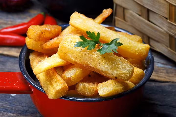 A bowl of crispy fried manioc sticks garnished with parsley, showcasing a popular Brazilian snack delight.